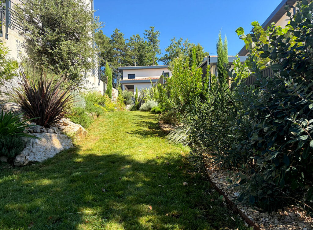 Allée de pelouse entre les massifs, sur le côté de la maison