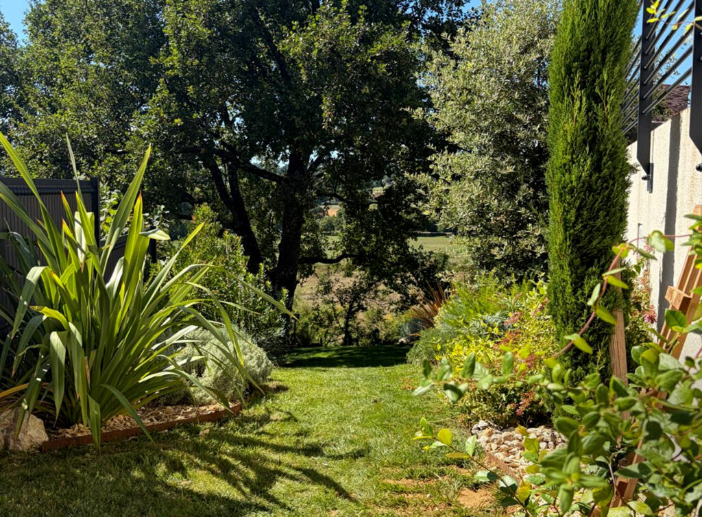 Phormiums, cyprès et massifs au pied de la façade